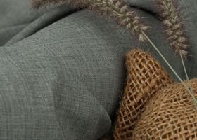 Close-up of ears of grain on gray fabric and net, showing rustic textures.