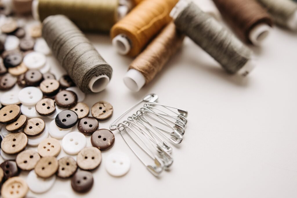 Close-up of sewing threads, buttons, and safety pins on a light background, perfect for craft projects.