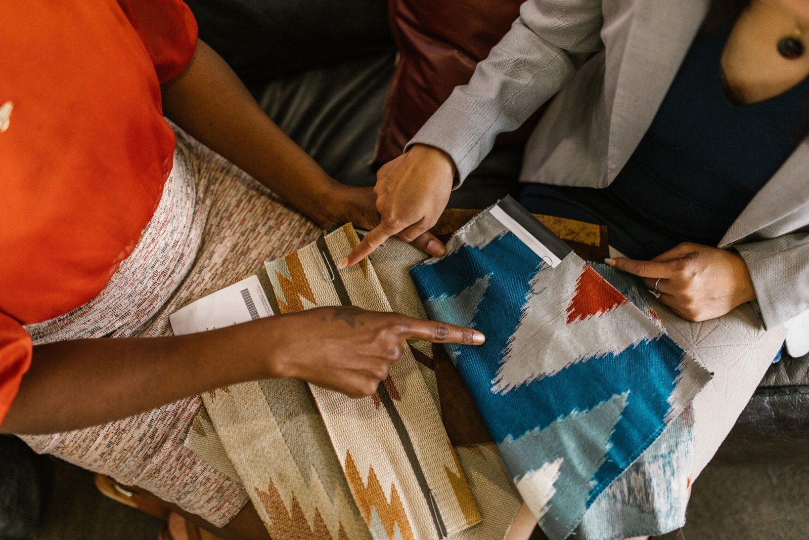 Two professionals assessing colorful fabric swatches for interior design project.